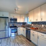 Custom modern kitchen with blue and white tile backsplash and white cabinets