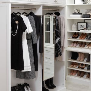 A custom walk-in closet with dresses hanging up and shoes on shelves.