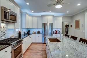 A luxury kitchen with quartz countertops, white cabinets, and stainless steel appliances.