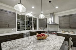 A beautiful modern kitchen with a kitchen island, stone countertops, and gray cabinets