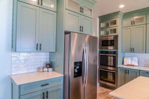 A modern kitchen with stainless steel appliances and light teal blue cabinetry