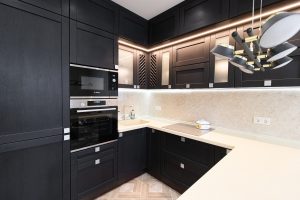 A beautiful modern kitchen with black cabinets and white countertops